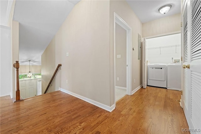 hallway featuring an upstairs landing, washing machine and clothes dryer, light wood-type flooring, and baseboards
