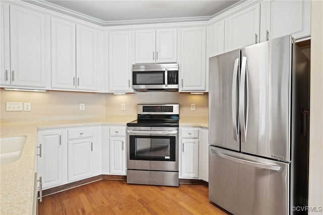 kitchen with appliances with stainless steel finishes, white cabinets, light countertops, and light wood finished floors