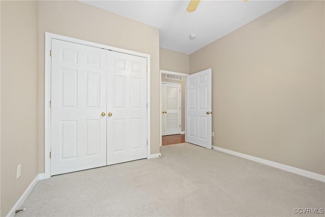 unfurnished bedroom with light colored carpet, a closet, baseboards, and a ceiling fan