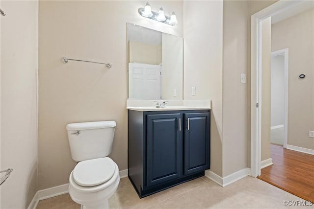 bathroom featuring toilet, vanity, and baseboards