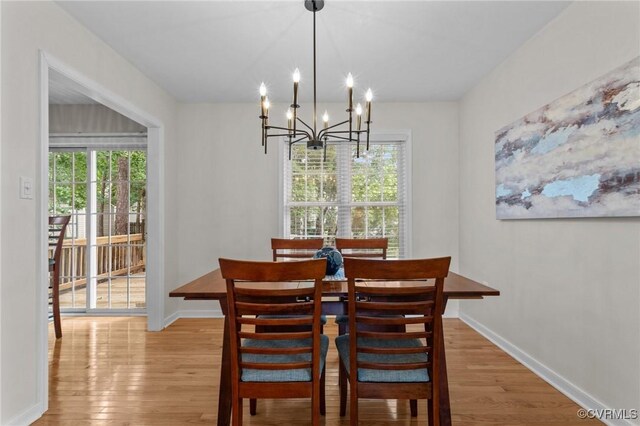 dining space with wood finished floors, a chandelier, and baseboards