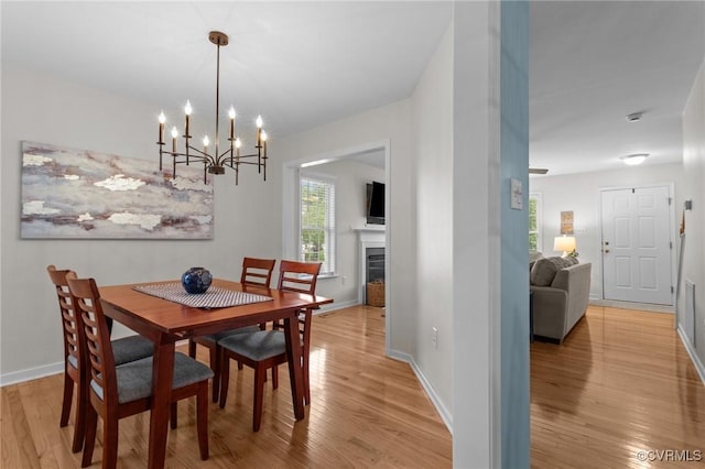 dining space featuring light wood finished floors, a chandelier, healthy amount of natural light, and baseboards