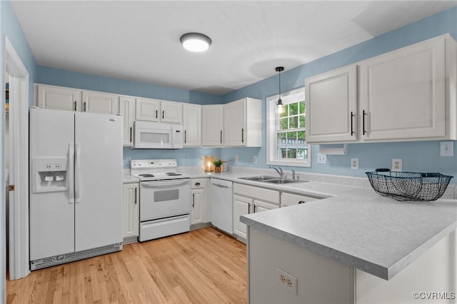 kitchen featuring white appliances, a sink, a peninsula, light countertops, and white cabinetry