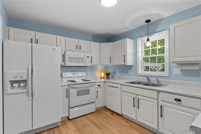 kitchen featuring white appliances, a sink, white cabinets, light countertops, and light wood-style flooring