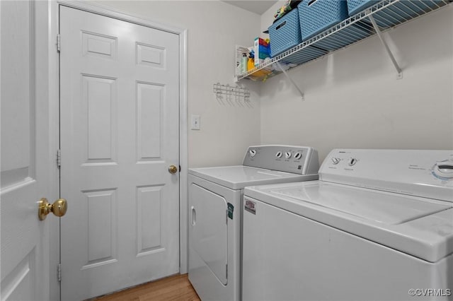laundry room featuring washer and clothes dryer and light wood finished floors