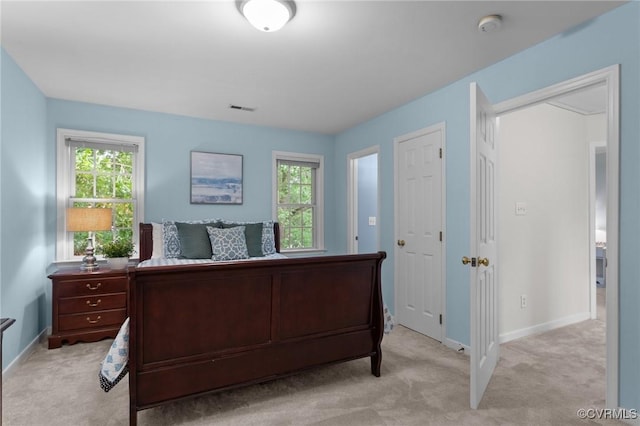 bedroom featuring light colored carpet, multiple windows, and baseboards