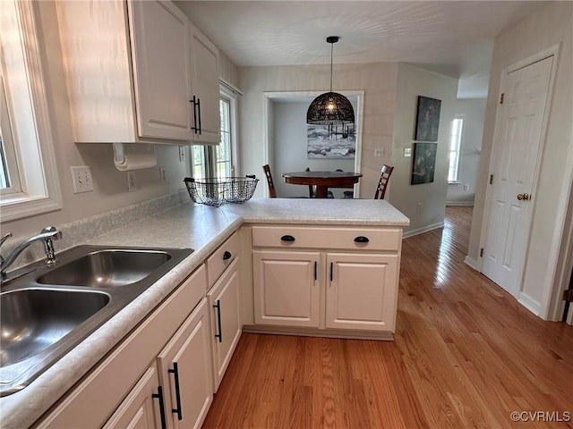 11441 Alder Glen Way, Glen Allen, VA 23059 - kitchen featuring light wood-style floors, a peninsula, a sink, white cabinets, and hanging light fixtures