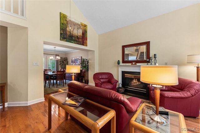11602 Hardwood Dr, Midlothian, VA 23114 - living area with high vaulted ceiling, baseboards, wood finished floors, a warm lit fireplace, and a chandelier