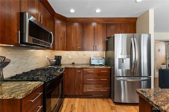 11602 Hardwood Dr, Midlothian, VA 23114 - kitchen with appliances with stainless steel finishes, light wood finished floors, dark stone counters, tasteful backsplash, and recessed lighting