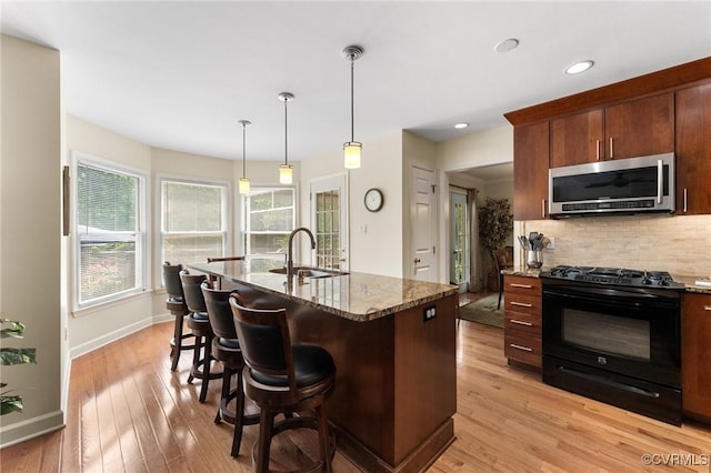 11602 Hardwood Dr, Midlothian, VA 23114 - kitchen featuring stainless steel microwave, black range with gas cooktop, a sink, decorative backsplash, and dark stone countertops