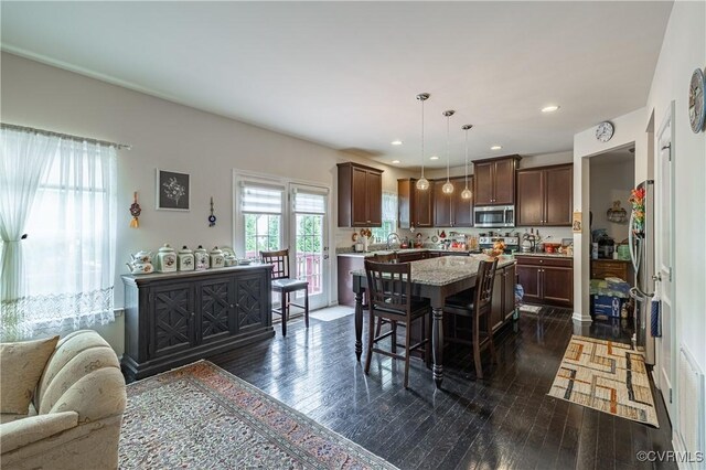 8421 Eden St, Henrico, VA 23228 - kitchen with appliances with stainless steel finishes, a kitchen island, dark brown cabinetry, dark wood finished floors, and a breakfast bar area