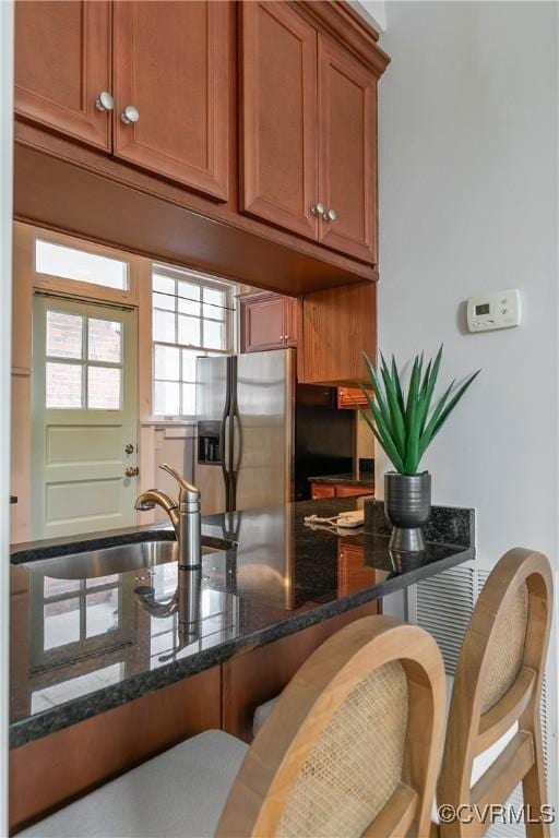 601 Roseneath Rd Unit U11, Richmond, VA 23221 - kitchen featuring stainless steel fridge, brown cabinetry, a breakfast bar, dark stone countertops, and a sink