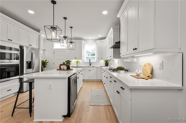 kitchen featuring stainless steel appliances, a sink, white cabinets, beverage cooler, and backsplash