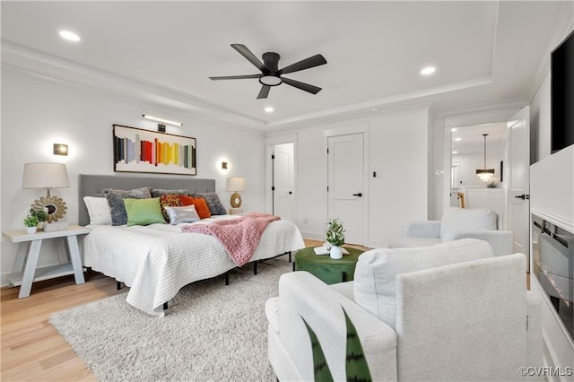 bedroom with light wood-style flooring, a tray ceiling, recessed lighting, and a ceiling fan