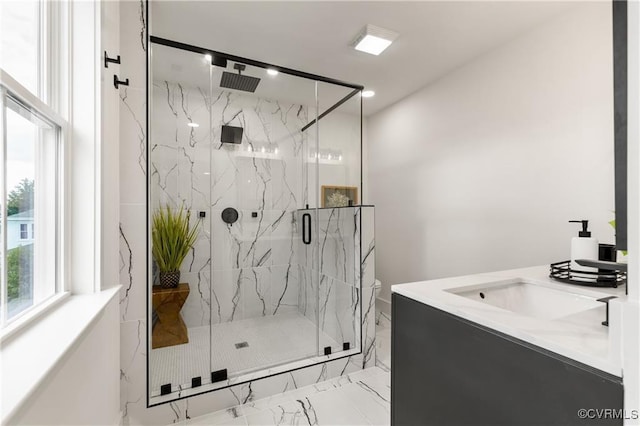 bathroom with marble look tile flooring, a marble finish shower, and a sink