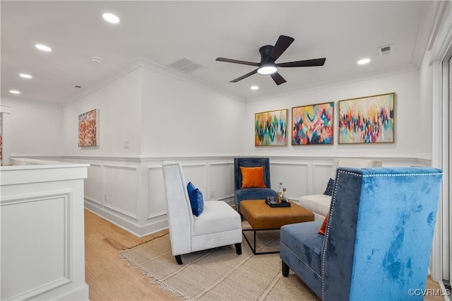 living area featuring ornamental molding, recessed lighting, a ceiling fan, light wood finished floors, and wainscoting