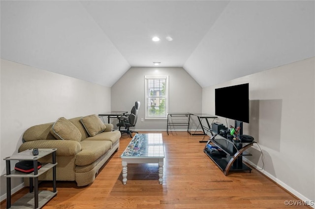 living area featuring wood finished floors, lofted ceiling, and baseboards