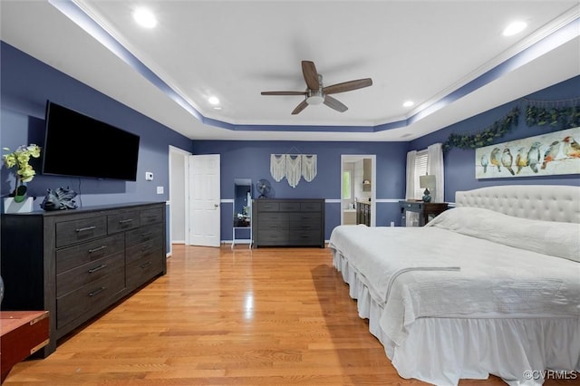 bedroom featuring a tray ceiling, light wood-type flooring, recessed lighting, connected bathroom, and a ceiling fan