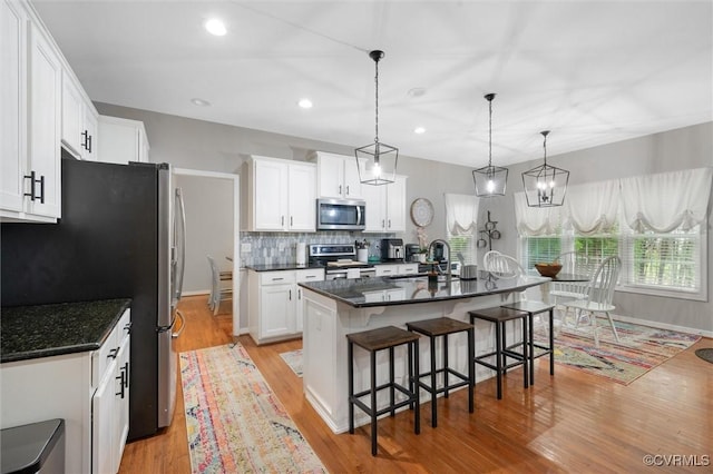 kitchen featuring appliances with stainless steel finishes, a sink, light wood finished floors, tasteful backsplash, and recessed lighting