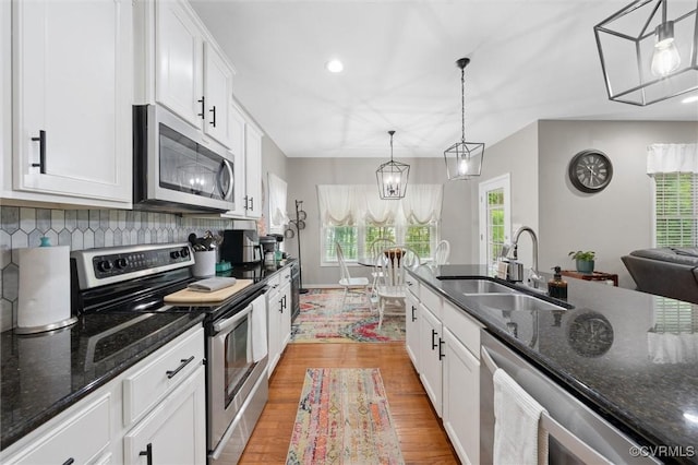 kitchen with stainless steel appliances, a sink, light wood-style floors, white cabinetry, and recessed lighting