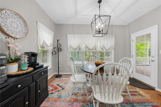 dining room with a chandelier, baseboards, and light wood-type flooring