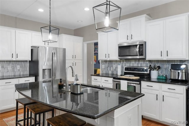 kitchen with appliances with stainless steel finishes, a sink, white cabinets, and recessed lighting