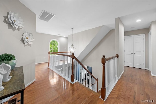 hallway featuring an upstairs landing, wood finished floors, and baseboards