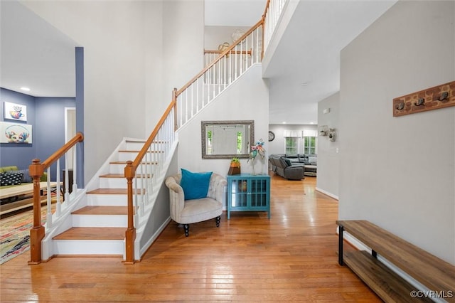 stairs featuring wood-type flooring, a high ceiling, and baseboards