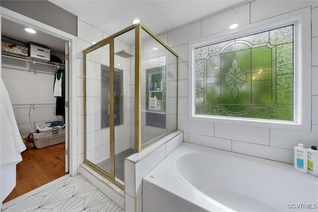 bathroom with a stall shower, a bath, and a spacious closet