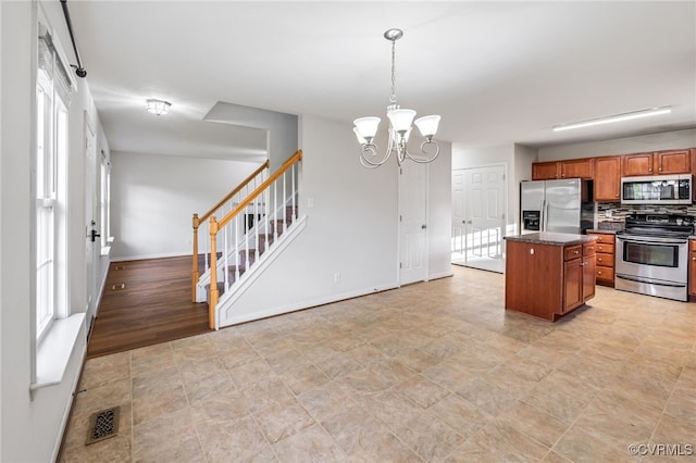 2909 Ginter St, Henrico, VA 23228 - kitchen with appliances with stainless steel finishes, brown cabinetry, a chandelier, a kitchen island, and baseboards