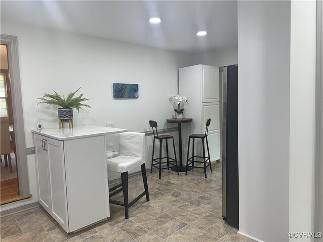 9079 Cudlipp Ave, Mechanicsville, VA 23116 - kitchen with stone finish floors, a kitchen bar, white cabinets, light countertops, and recessed lighting