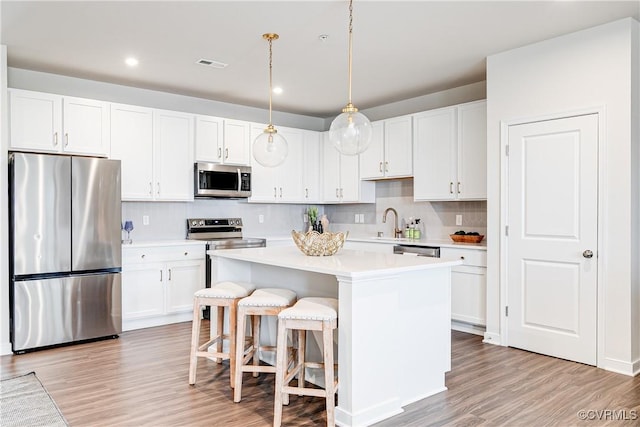 1900 Roseneath Rd Unit 9A, Richmond, VA 23230 - kitchen featuring appliances with stainless steel finishes, light countertops, a center island, white cabinets, and light wood-type flooring