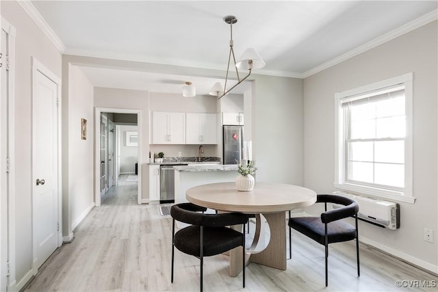 dining area with light wood-style floors, crown molding, and baseboards