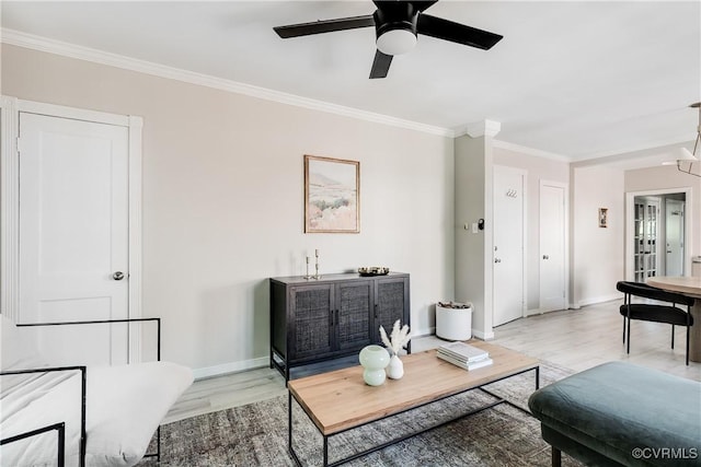 living room with light wood-style floors, crown molding, a ceiling fan, and baseboards