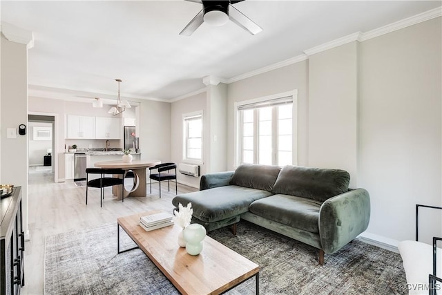 living room with ceiling fan, light wood-type flooring, crown molding, and baseboards
