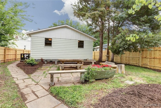 1909 N 28th St, Richmond, VA 23223 - back of property with board and batten siding, a fenced backyard, and a vegetable garden