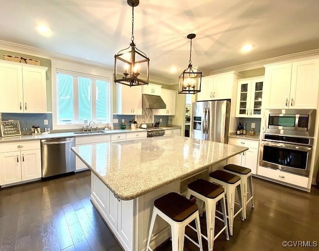 kitchen featuring stainless steel appliances, under cabinet range hood, a chandelier, a sink, and crown molding