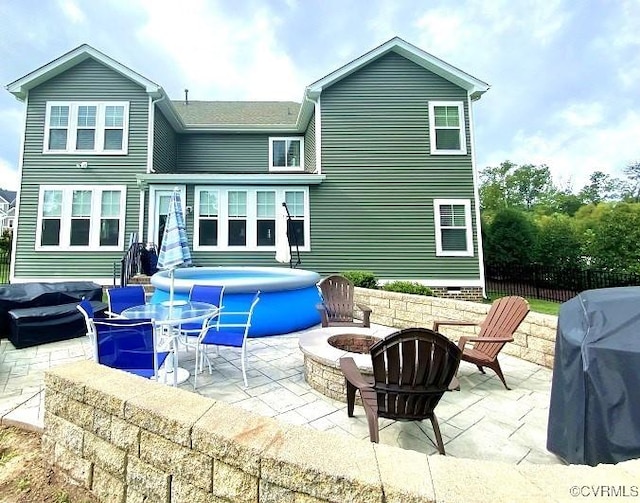rear view of property with a fire pit, a patio, and fence