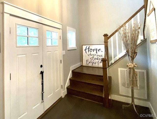 foyer entrance with stairs and baseboards