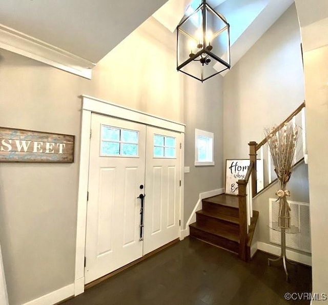 foyer with stairway, baseboards, a chandelier, dark wood-type flooring, and a high ceiling