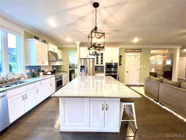 kitchen featuring stainless steel appliances, a sink, extractor fan, a chandelier, and white cabinets