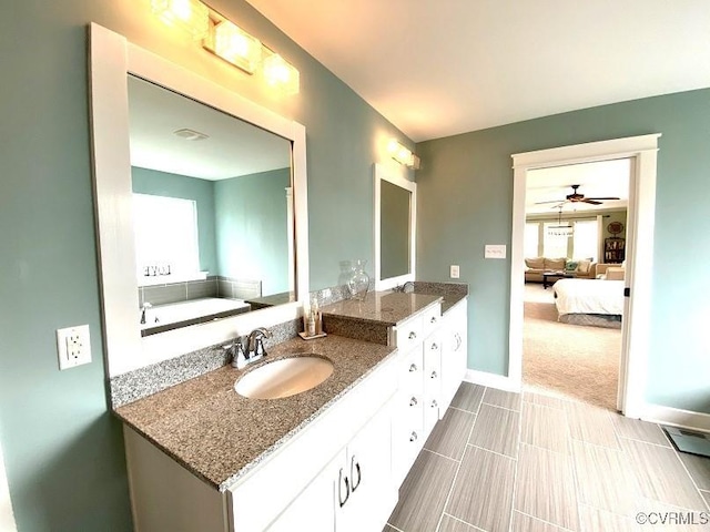 full bath featuring connected bathroom, double vanity, baseboards, and ceiling fan