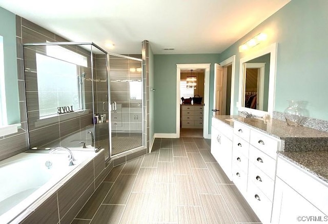 full bathroom featuring a shower stall, a spacious closet, a garden tub, vanity, and baseboards