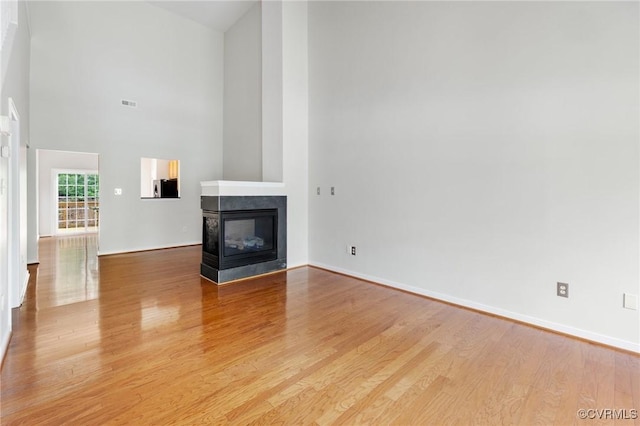 2409 Silver Lake Ter, Midlothian, VA 23112 - unfurnished living room with light wood-type flooring, a multi sided fireplace, baseboards, and a high ceiling