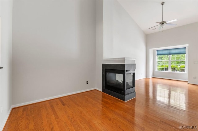 2409 Silver Lake Ter, Midlothian, VA 23112 - unfurnished living room featuring high vaulted ceiling, wood finished floors, baseboards, ceiling fan, and a multi sided fireplace