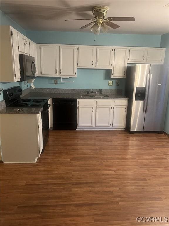 kitchen with black appliances, a sink, dark countertops, and white cabinetry