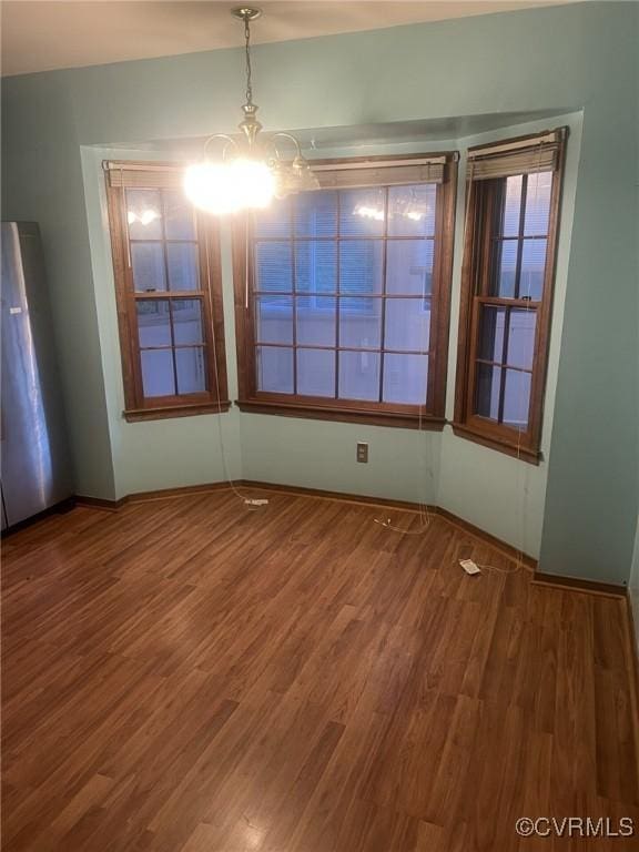 unfurnished dining area featuring a chandelier and wood finished floors