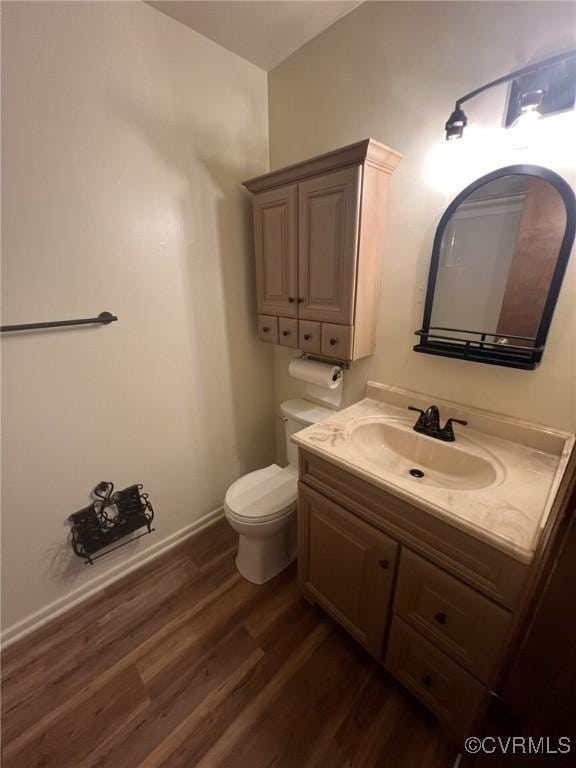 bathroom featuring wood finished floors, toilet, and vanity