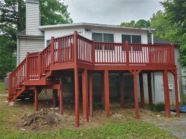 back of property with a wooden deck, a chimney, and stairway