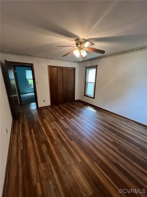 unfurnished bedroom with dark wood-style floors, multiple windows, a closet, and ceiling fan